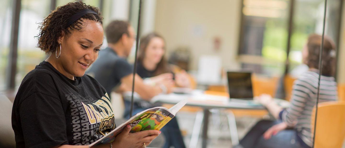 一名身穿黑色十大菠菜台子衬衫的女学生正在读书