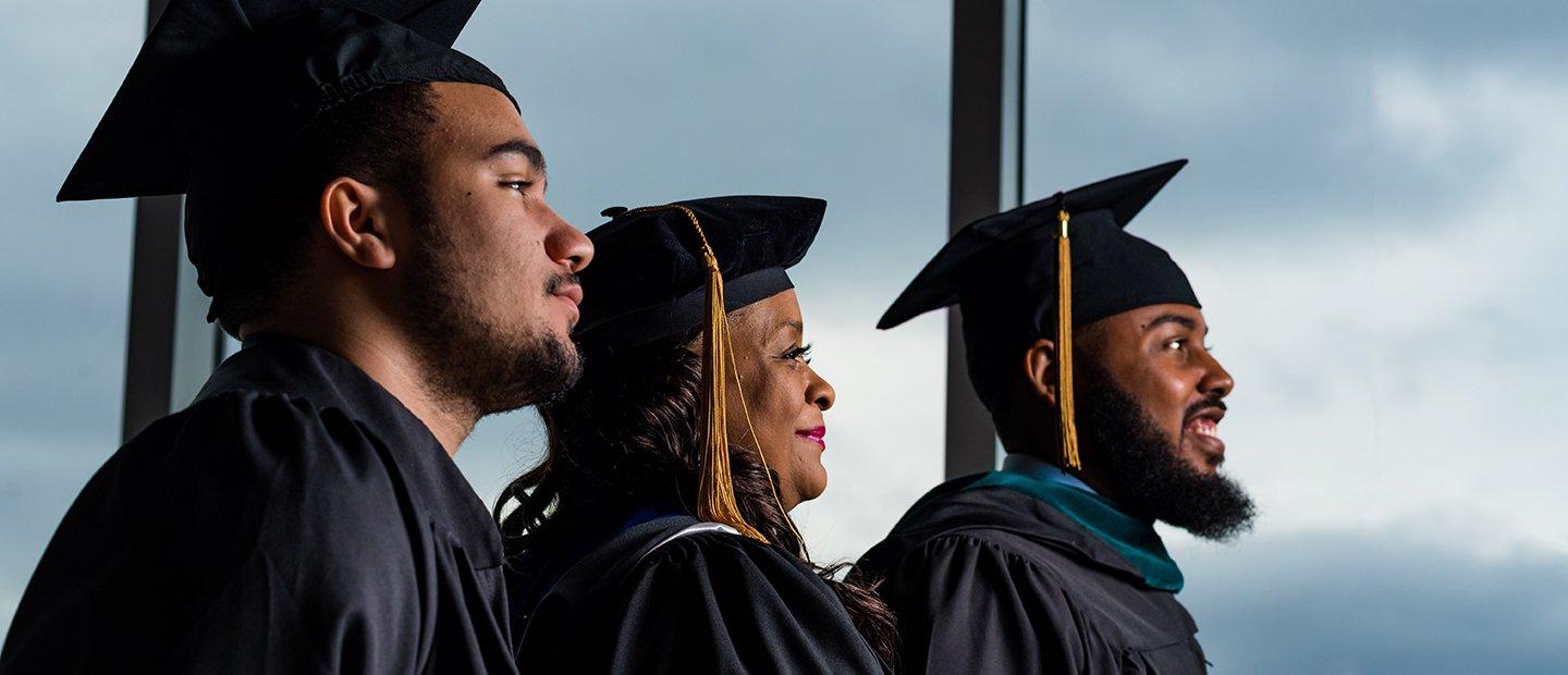 三个非裔美国学生戴着毕业帽，穿着毕业服.